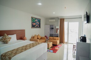 Ein Hotelzimmer mit einem Bett, zwei Sofas, einem Couchtisch, einem Fernseher und einem Fenster mit Vorhängen.