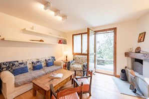 A living room with a sofa, coffee table, chairs, a fireplace, and a large window.
