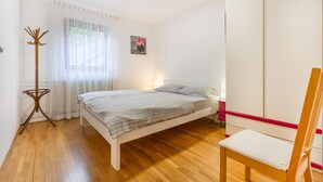 A bedroom with a bed, a chair, a coat rack, and a window with curtains. - 1 bedroom gorgeous apartment in Dekani (Dekani)