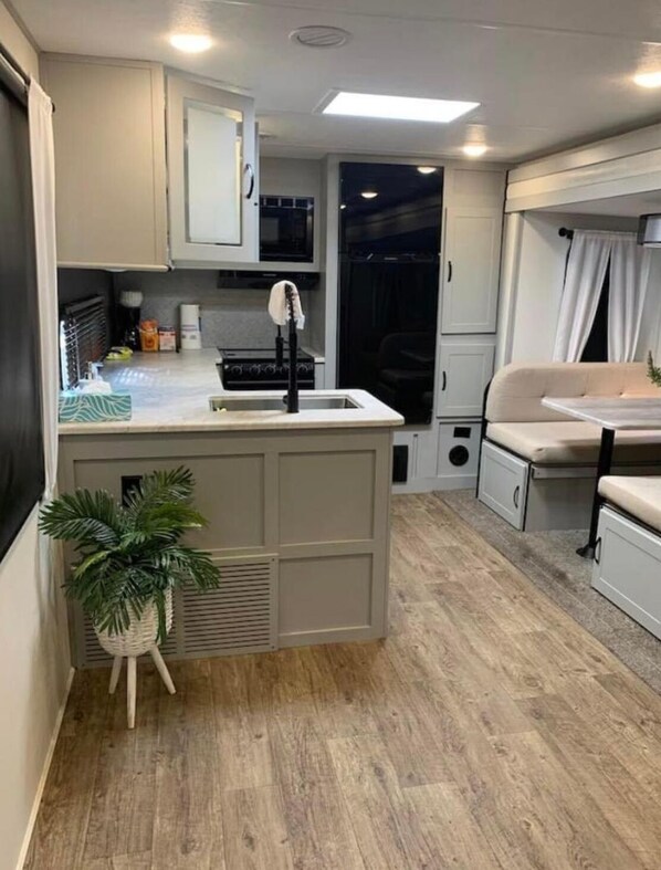 Een compacte RV-keuken met een centraal eiland, een spoelbak en een kookplaat.