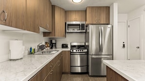 Eine kleine Küche mit Holzausstattung, einer Edelstahl-Mikrowelle, einem Backofen und einem Kühlschrank.