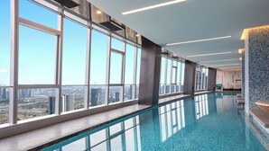 A modern indoor swimming pool with large windows offering city views. - Fraser Place Chengdu  (Chengdu)