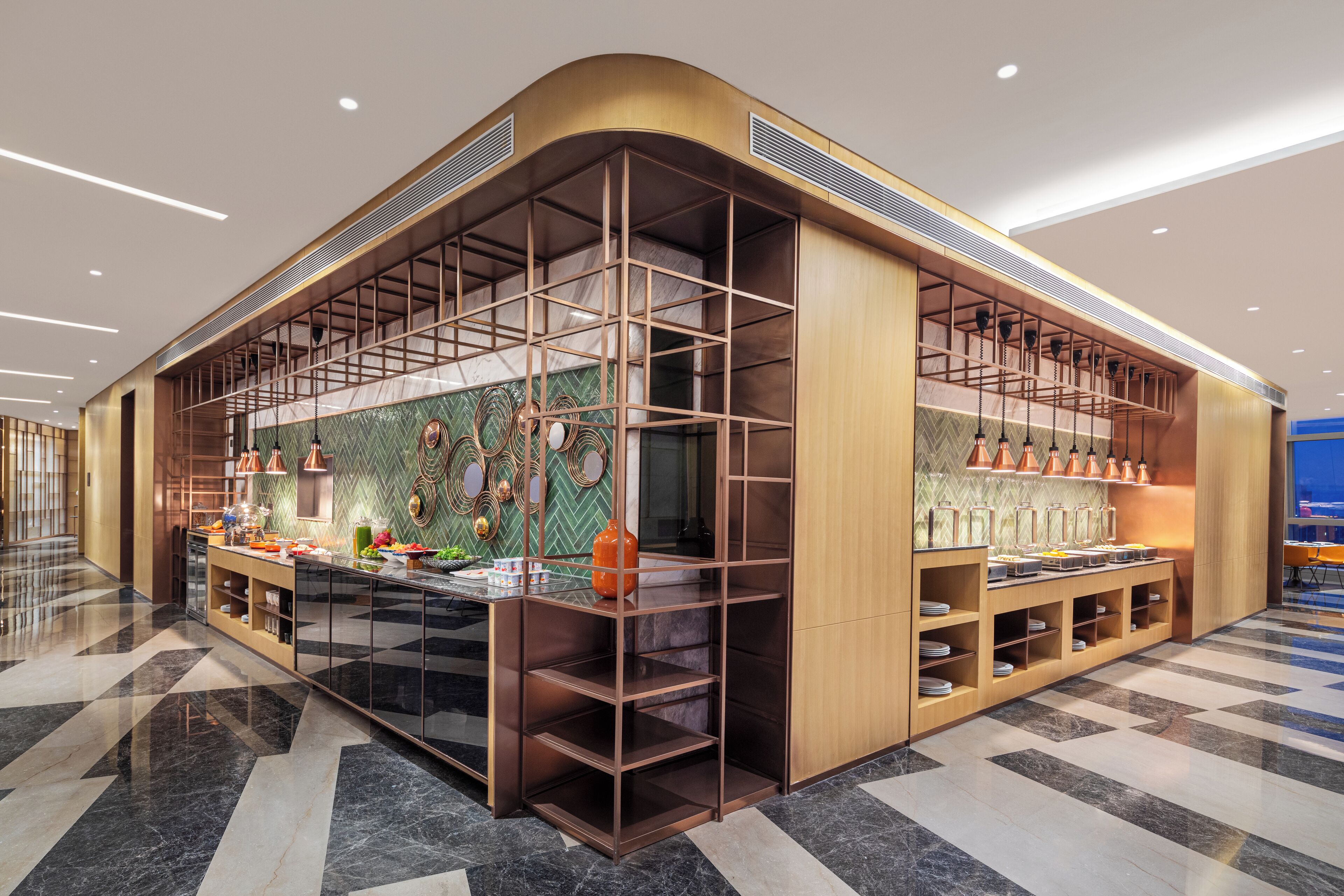 A modern hotel lobby with a curved reception desk, a green herringbone-patterned wall, and a checkered floor.
