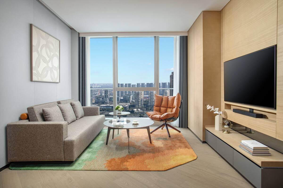 A modern living room with a sofa, armchair, coffee table, and a large TV.