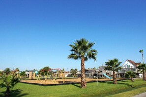 Relax in a serene outdoor space surrounded by lush greenery and a playground for kids.