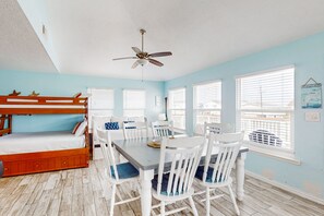 Cozy retreat with a bunk bed, dining table, and ceiling fan, perfect for a relaxing stay.