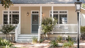 A house with a front porch, a small tree, and a pathway.