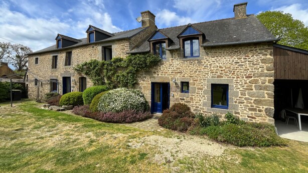 Un bâtiment en pierre doté de nombreuses fenêtres et d’une porte bleue.