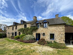 Un bâtiment en pierre doté de nombreuses fenêtres et d’une porte bleue.