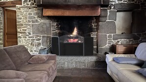 Une cheminée en pierre avec un feu, flanquée de deux canapés, un de chaque côté.