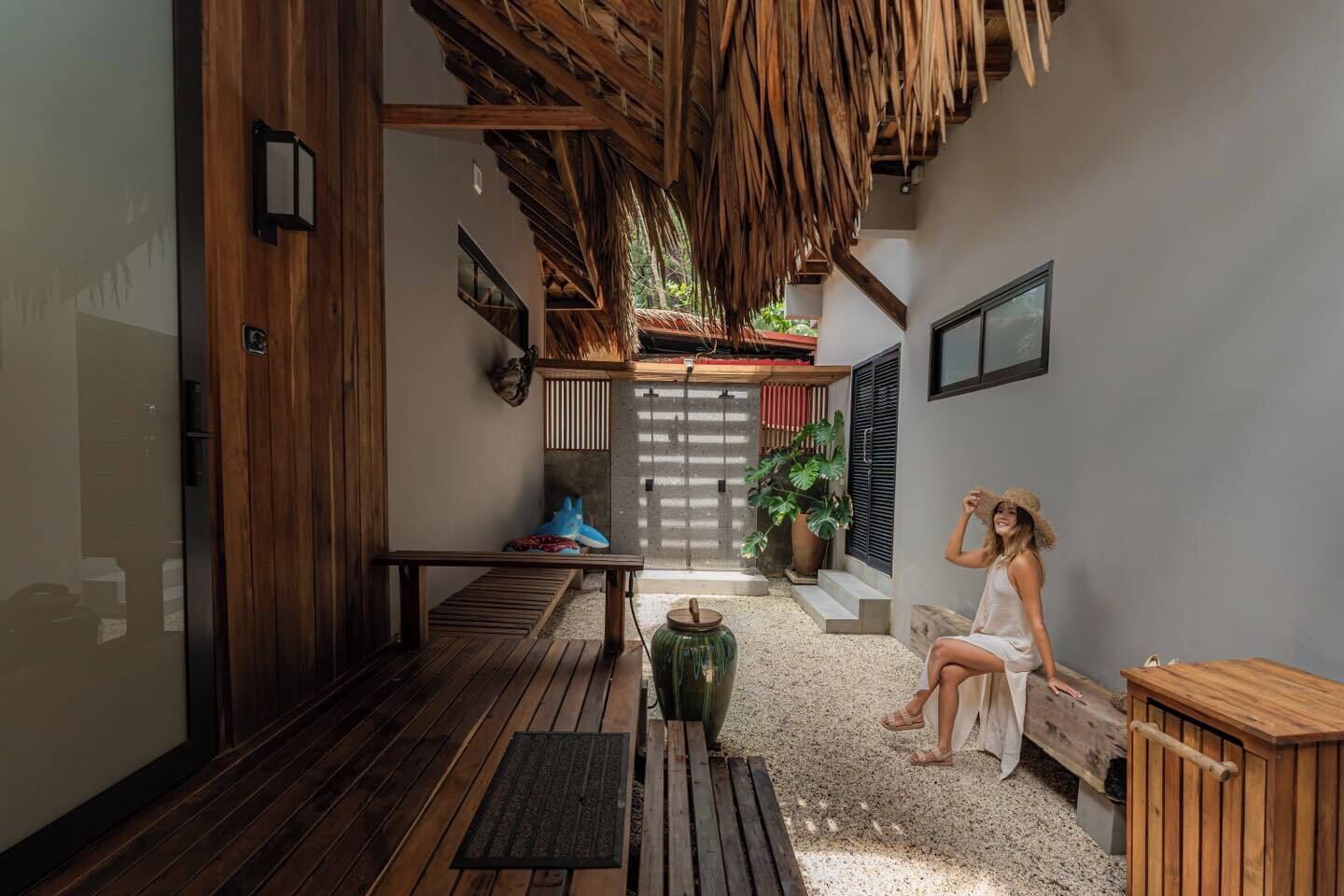 Un espacio al aire libre cubierto con un banco de madera, una mesita y un cubo de basura.