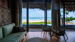 A room with a large glass door leading to a beach view, a sofa, two chairs, and a small table. - Sealord Naithon Beach Phuket (Sa Khu)