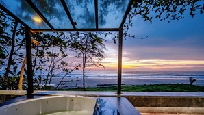 A glass-enclosed outdoor area with a hot tub, overlooking a beach at sunset. - Sealord Naithon Beach Phuket (Sa Khu)