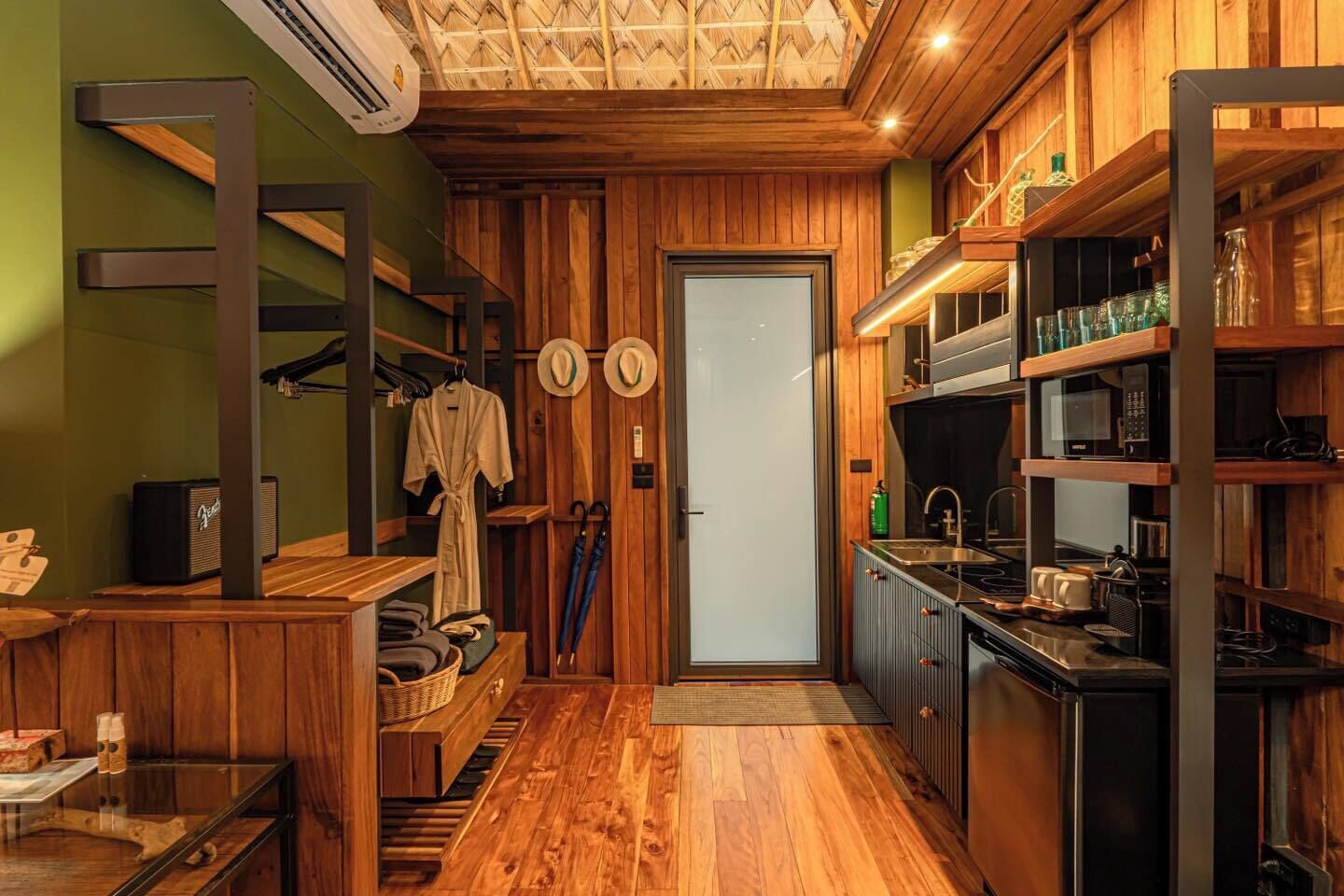 Una cocina compacta con armarios de madera, un microondas integrado y un lavamanos.