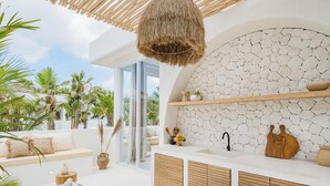 Una cocina moderna con protector contra salpicaduras de piedra, armarios de madera y una lámpara colgante.