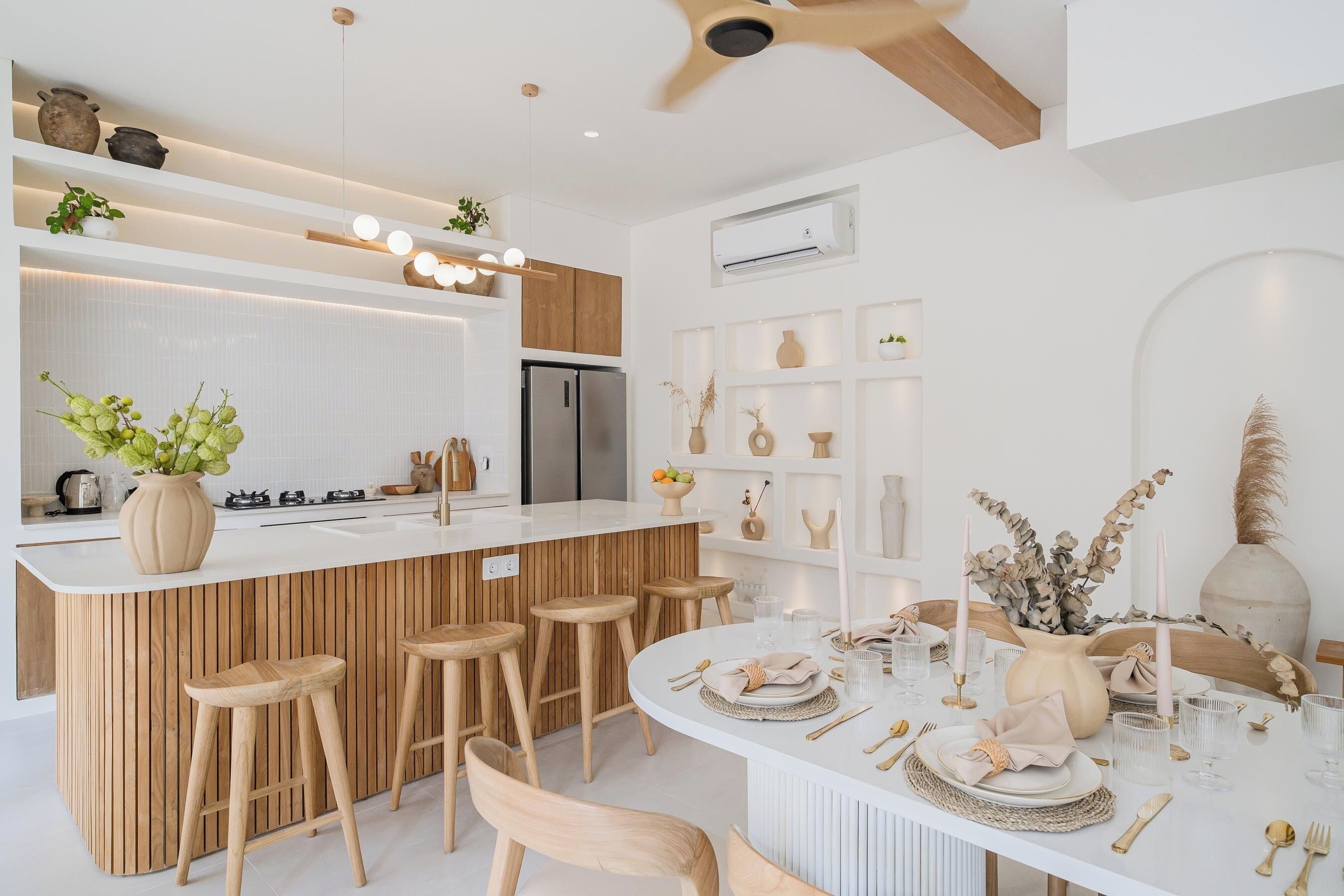 Una cocina moderna con una isla de madera, taburetes de bar y un comedor listo para una comida.