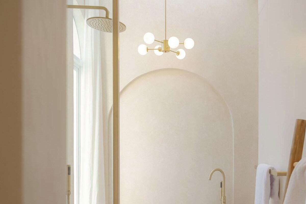 A modern bathroom with a freestanding bathtub, a wooden side table with toiletries, and a hanging light fixture.