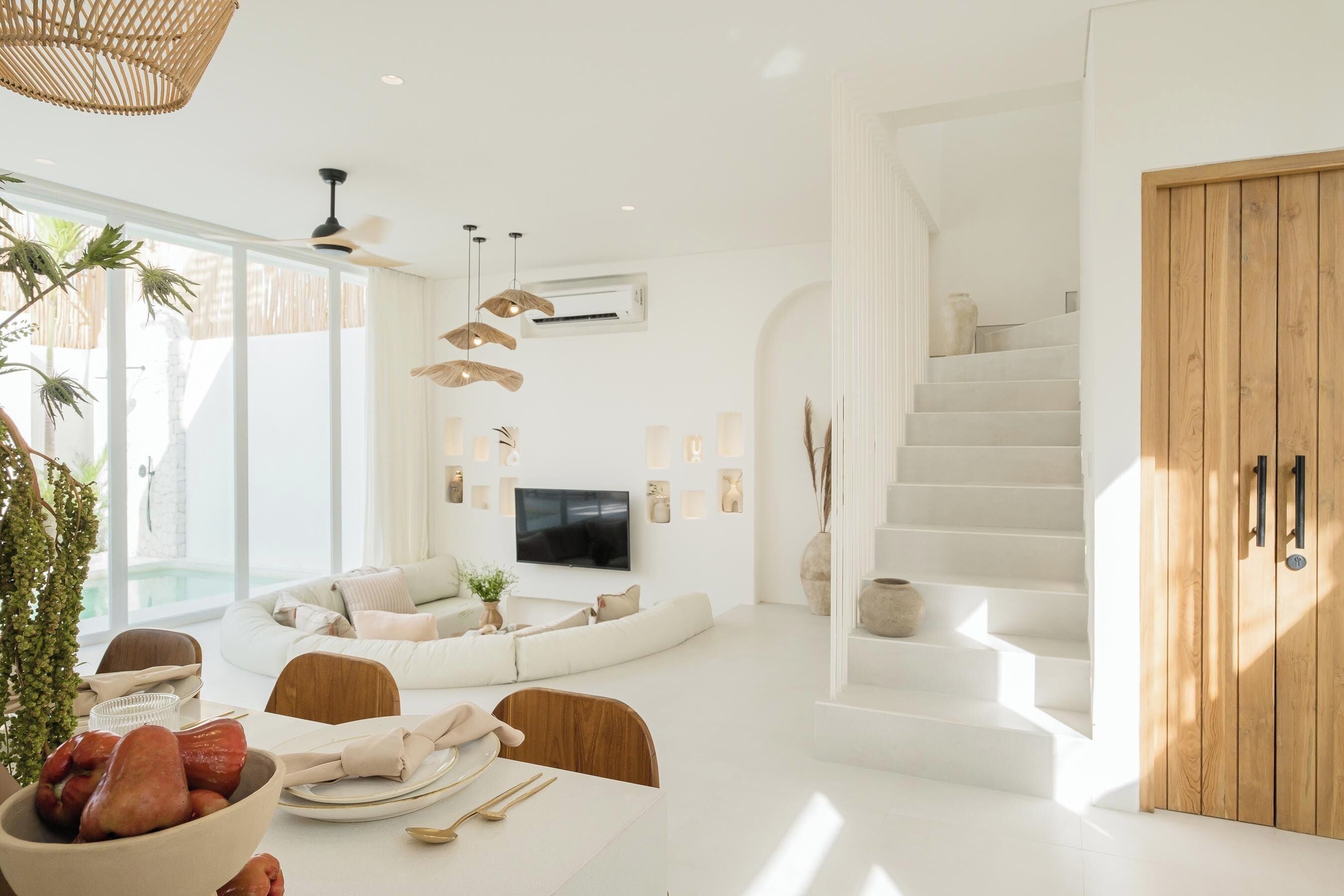 A modern living room with a sofa, dining table, and staircase.