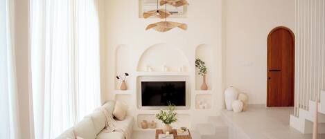 A modern living room with a sofa, TV, and decorative items.