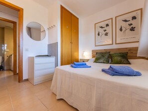 A bedroom with a bed, a dresser, a mirror, and two framed floral artworks on the wall. - Lovely apartment for 4 people with pool, WIFI, A/C, TV and terrace (Salou)
