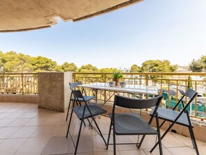 A balcony with a table and chairs, a potted plant, and a view of trees and buildings. - Lovely apartment for 4 people with pool, WIFI, A/C, TV and terrace (Salou)