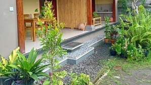 Una casa con un porche cubierto, un comedor y una cocina visible a través de la puerta abierta.