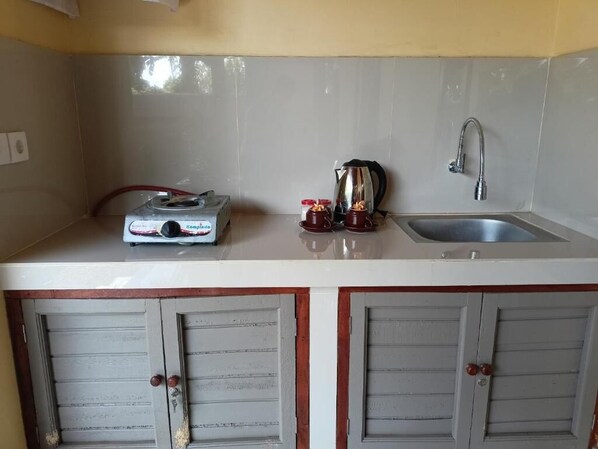 Una cocina con estufa a gas, hervidor y pileta.