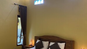 Un dormitorio con una cama grande, cabecera de madera, dos mesitas de noche con lámparas y una ventana con cortinas.