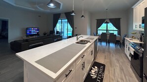 Una cocina moderna con una isla central, electrodomésticos integrados e iluminación colgante.