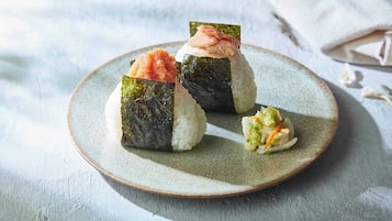 A plate with three sushi pieces and a small salad on a ceramic plate.