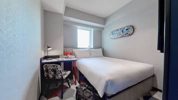 Ein kleines Hotelzimmer mit einem Bett, einem Schreibtisch und einem Stuhl.
