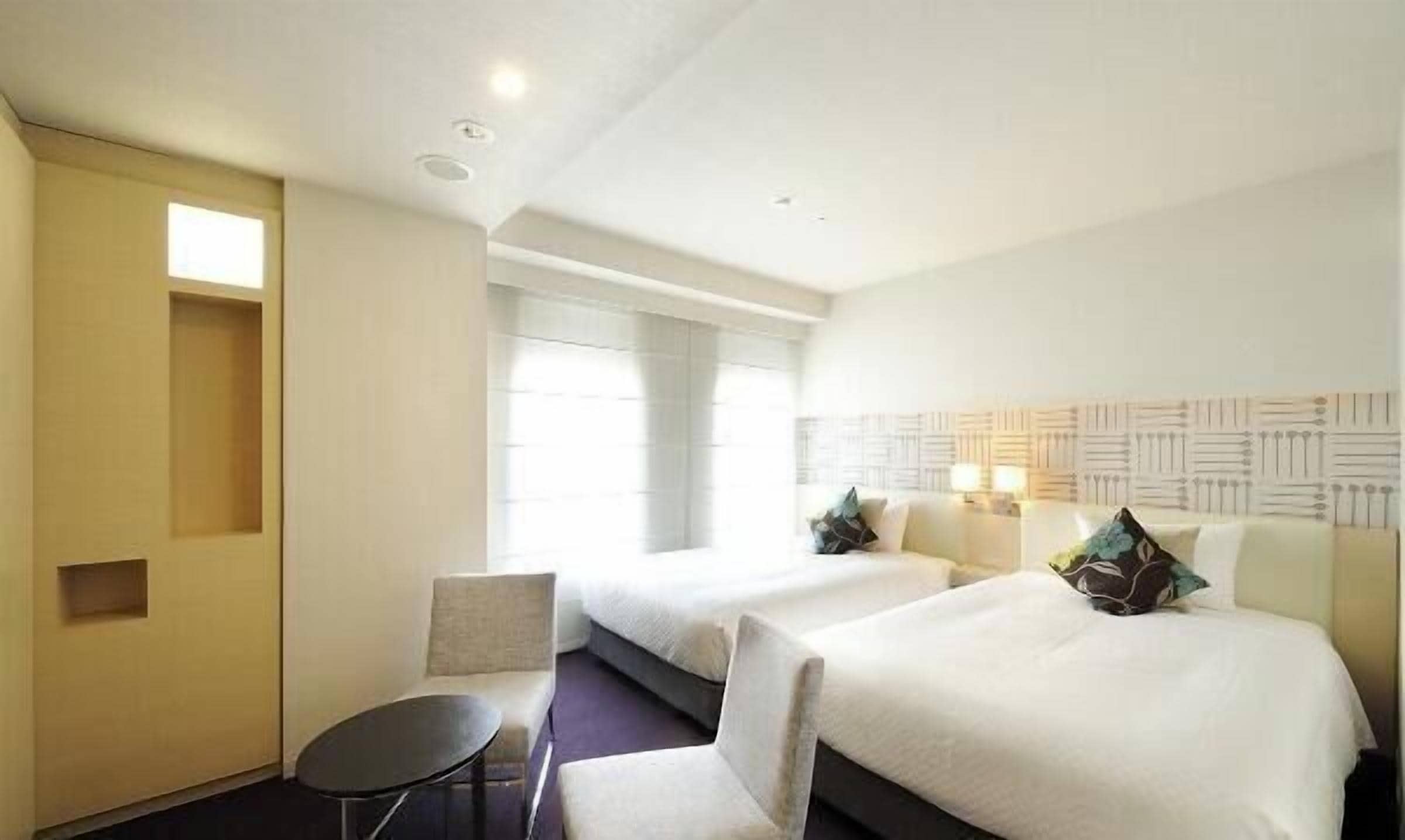 Une chambre d’hôtel avec deux lits, une petite table et une chaise.