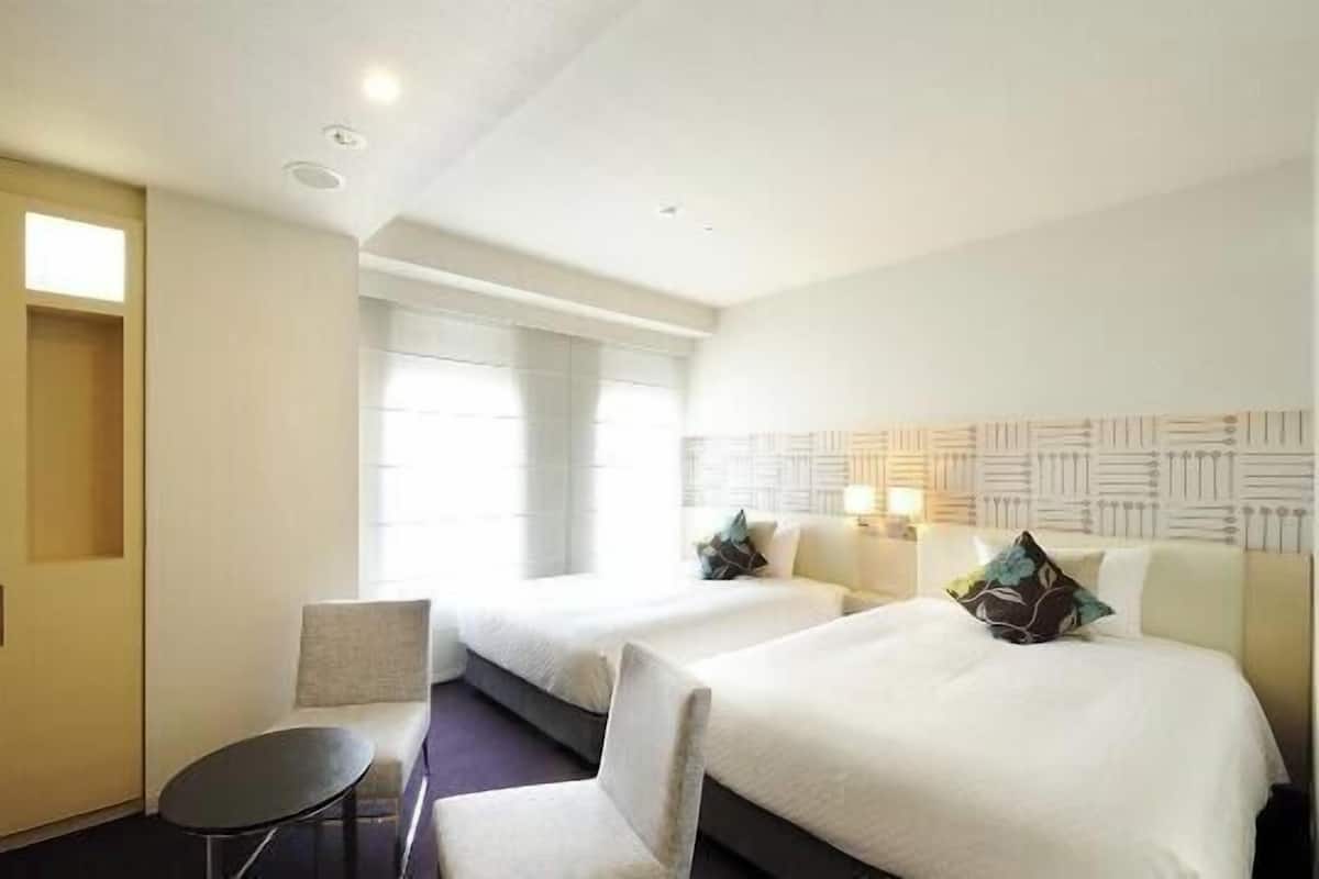 Une chambre d’hôtel avec deux lits, une petite table et une chaise.