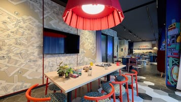 Un comedor moderno con una mesa larga, sillas coloridas y una lámpara colgante roja.