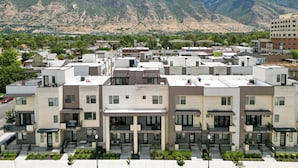 A modern apartment complex with multiple buildings, featuring balconies, a central courtyard, and a mountainous backdrop. - Superb 4-bedroom townhome in Provo with AC, WiFi (Provo)