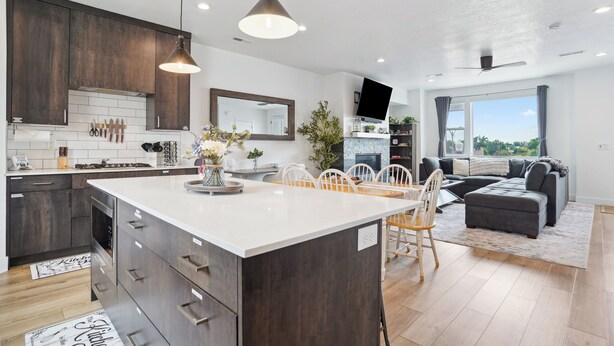 A modern kitchen with dark wood cabinets, a white island, and pendant lighting. - Superb 4-bedroom townhome in Provo with AC, WiFi (Provo)