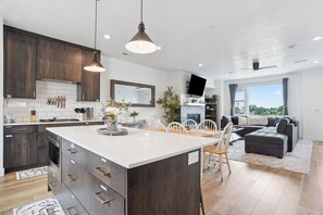 A modern kitchen with dark wood cabinets, a white island, and pendant lighting. - Superb 4-bedroom townhome in Provo with AC, WiFi (Provo)
