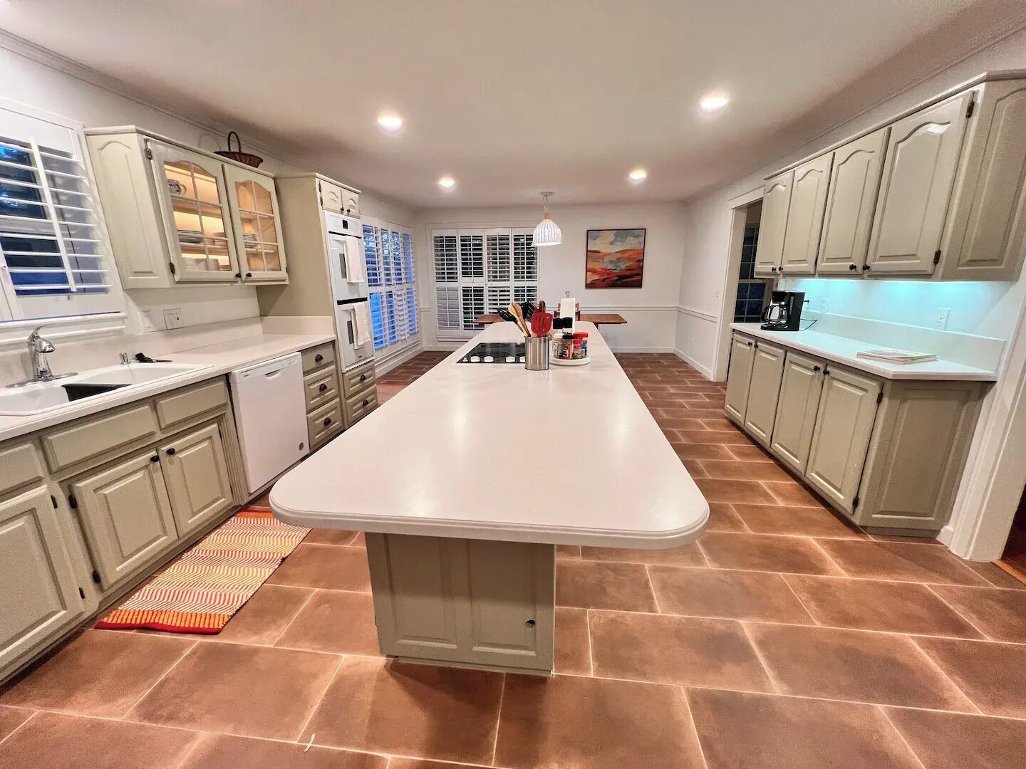 Una cocina moderna con armarios blancos, una isla central y piso de baldosas.