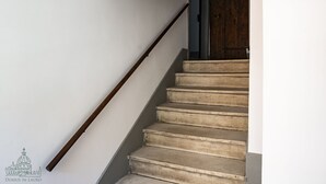 A staircase with a wooden handrail and concrete steps leading to a dark wooden door. - Domus in Lauro (Coronari) (Roma)