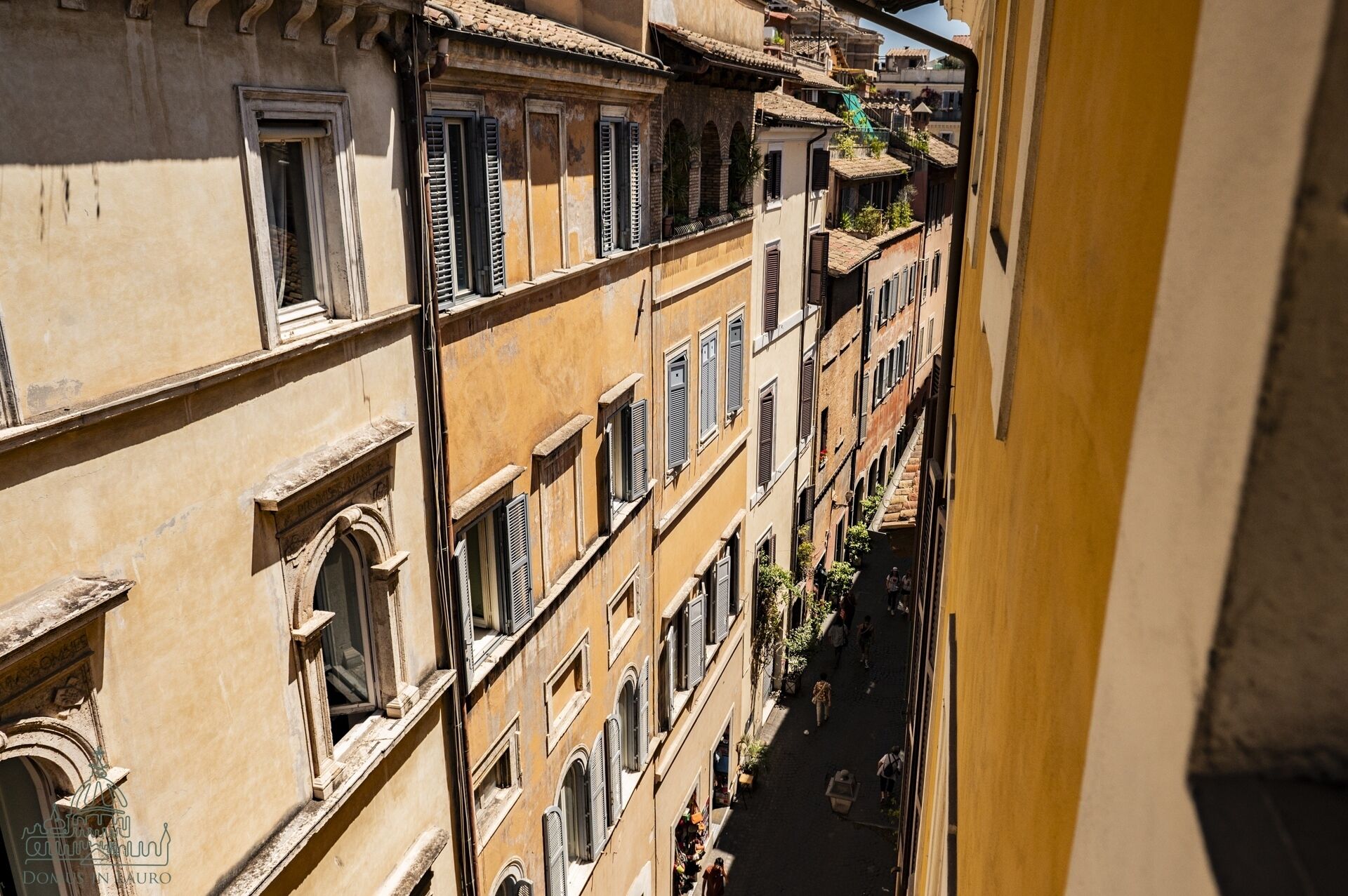 A narrow street with buildings featuring arched windows and shutters.