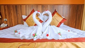 Un llit d'hotel amb un arranjament decoratiu de cignes fet amb almoades i una manta, i una almoada amb forma de cor que mostra el nom de l'hotel.