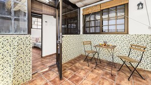 Un patio con suelo de baldosas, una mesa con sillas y una ventana con vistas.