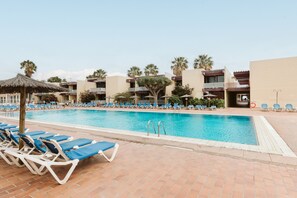 Un espace piscine doté de chaises longues et d’une piscine à l’eau d’un bleu cristallin.