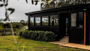 Un bâtiment moderne de couleur noire, doté de grandes fenêtres et d’une pelouse bien entretenue.