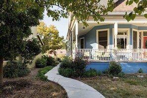 A blue house with a white porch and a pathway leading to it.