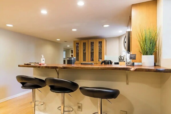 A modern kitchen with a wooden countertop, three bar stools, and a potted plant. - Charming 2-bedroom in historic home (Portland)