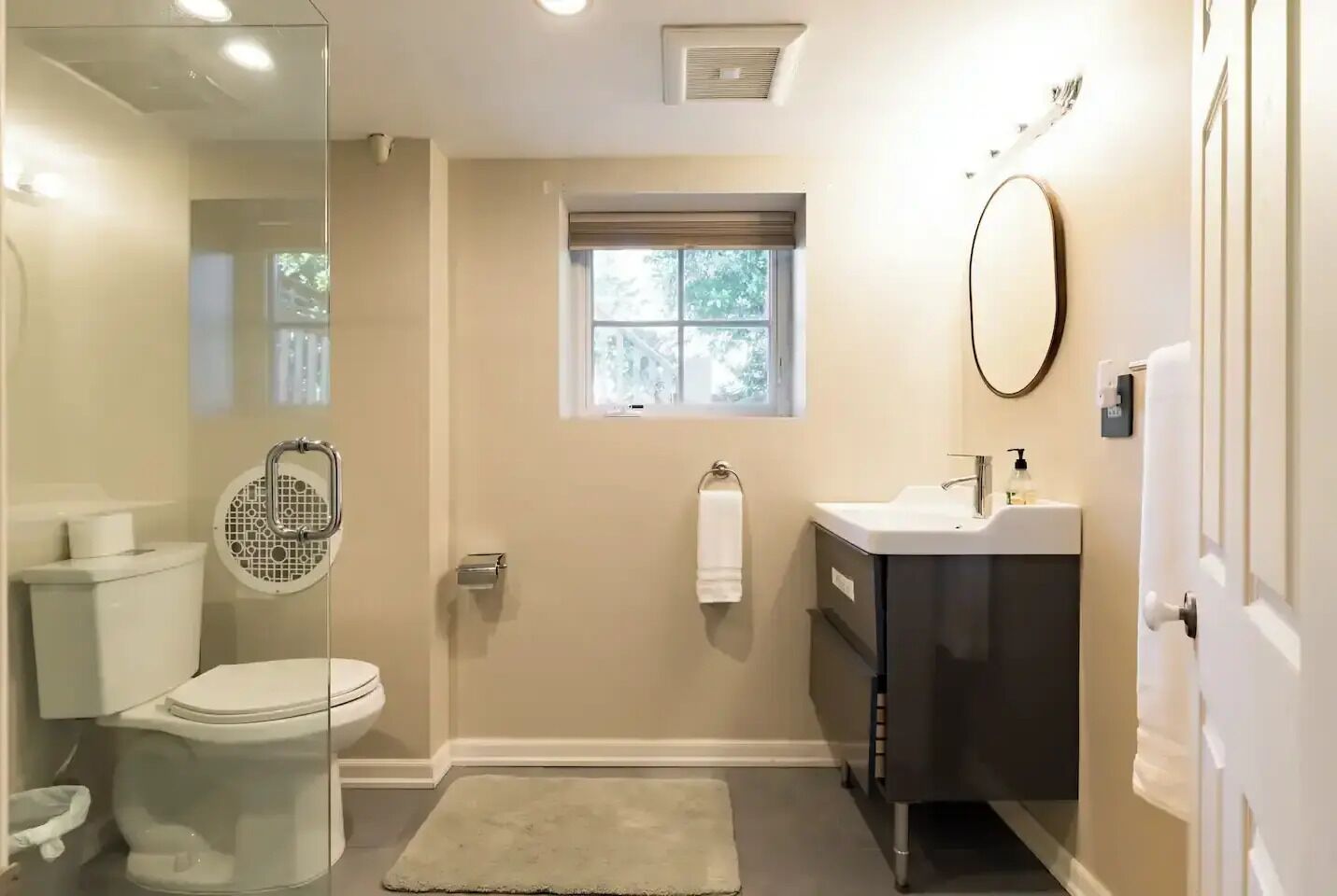 Un bagno con il water, un lavandino, uno specchio e una finestra.