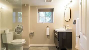 Un bagno con il water, un lavandino, uno specchio e una finestra.