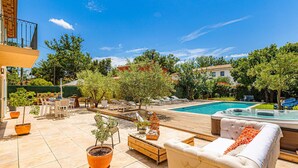 Zona de piscina con jacuzzi, sillas de descanso y plantas en macetas.