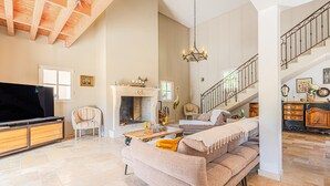 Un salón espacioso con chimenea, una escalera y un televisor.